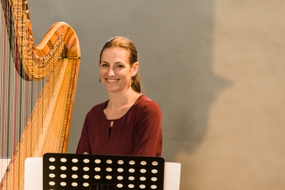 Bettina Linck, lachend an der Harfe. Aufgenommen in Malans in Graubünden. Das Foto stammt von Rüdiger Döls