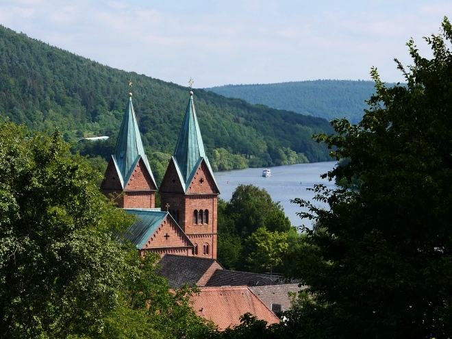 Blick auf Kloster Neustadt und den Main mit Schiff. Wer die Schiffe, vorbeigleiten sieht, spürt sie: Die Feier der Gemächlichkeit.